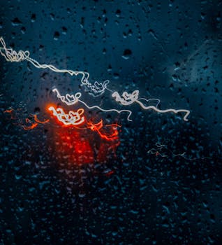 A creative night scene with raindrops and vibrant light patterns on glass, showcasing an abstract, moody atmosphere.