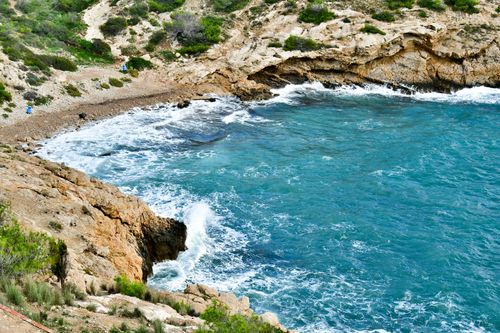 Free A stunning view of rocky shores and azure waves at Cala Tio Ximo in Spain, showcasing natural beauty. Stock Photo