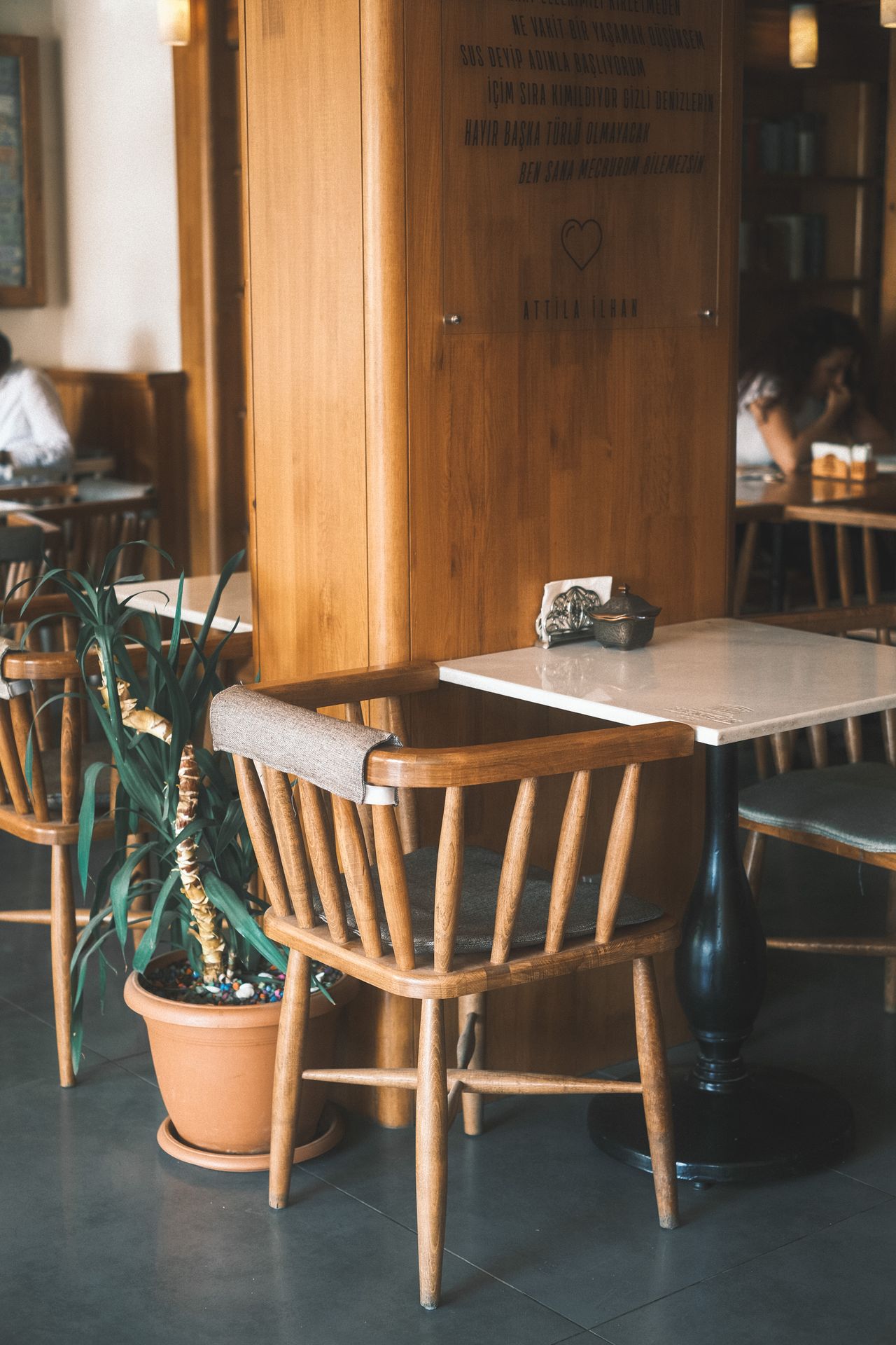 Spindle-back wooden captain's chair with arms at a marble cafe table