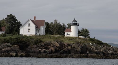 Free Serene view of a lighthouse and house on a rocky island, ideal for travel enthusiasts. Stock Photo