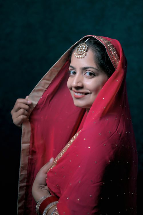 Free Captivating portrait of a woman in red dupatta with traditional maang tikka, exuding elegance. Stock Photo
