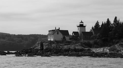 Black and White Photo of Lighthouse on Rocky Shore