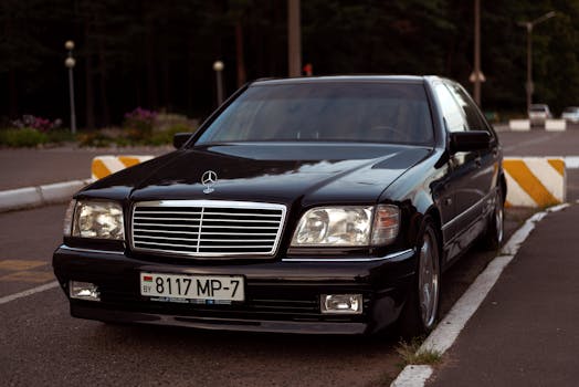 A sleek black Mercedes Benz luxury car parked outdoors on a clear day.