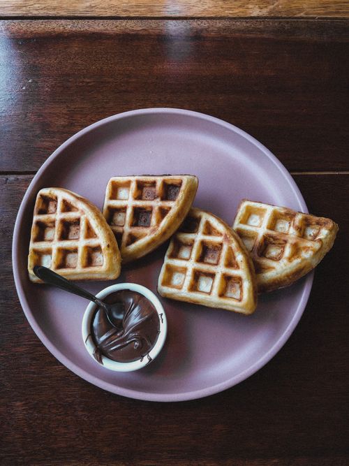 Free Top view of waffles with chocolate dip on a pink plate, perfect for breakfast or dessert. Stock Photo