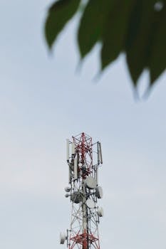Low angle view of a telecommunication tower with antennae against a clear sky.