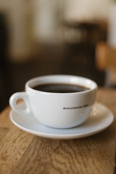 A close-up of a steaming cup of black coffee on a saucer, perfect for a cozy morning moment.