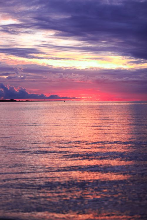 Free A breathtaking sunset over a tranquil ocean with vibrant pink and purple hues. Stock Photo