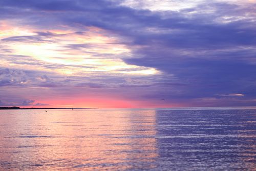 Free A breathtaking view of the ocean with pink and purple hues during a vibrant sunset. Stock Photo