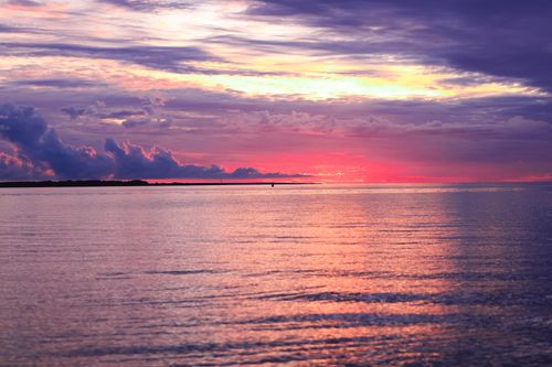 Free Beautiful ocean sunset with vibrant pink and purple skies reflecting on the water. Stock Photo