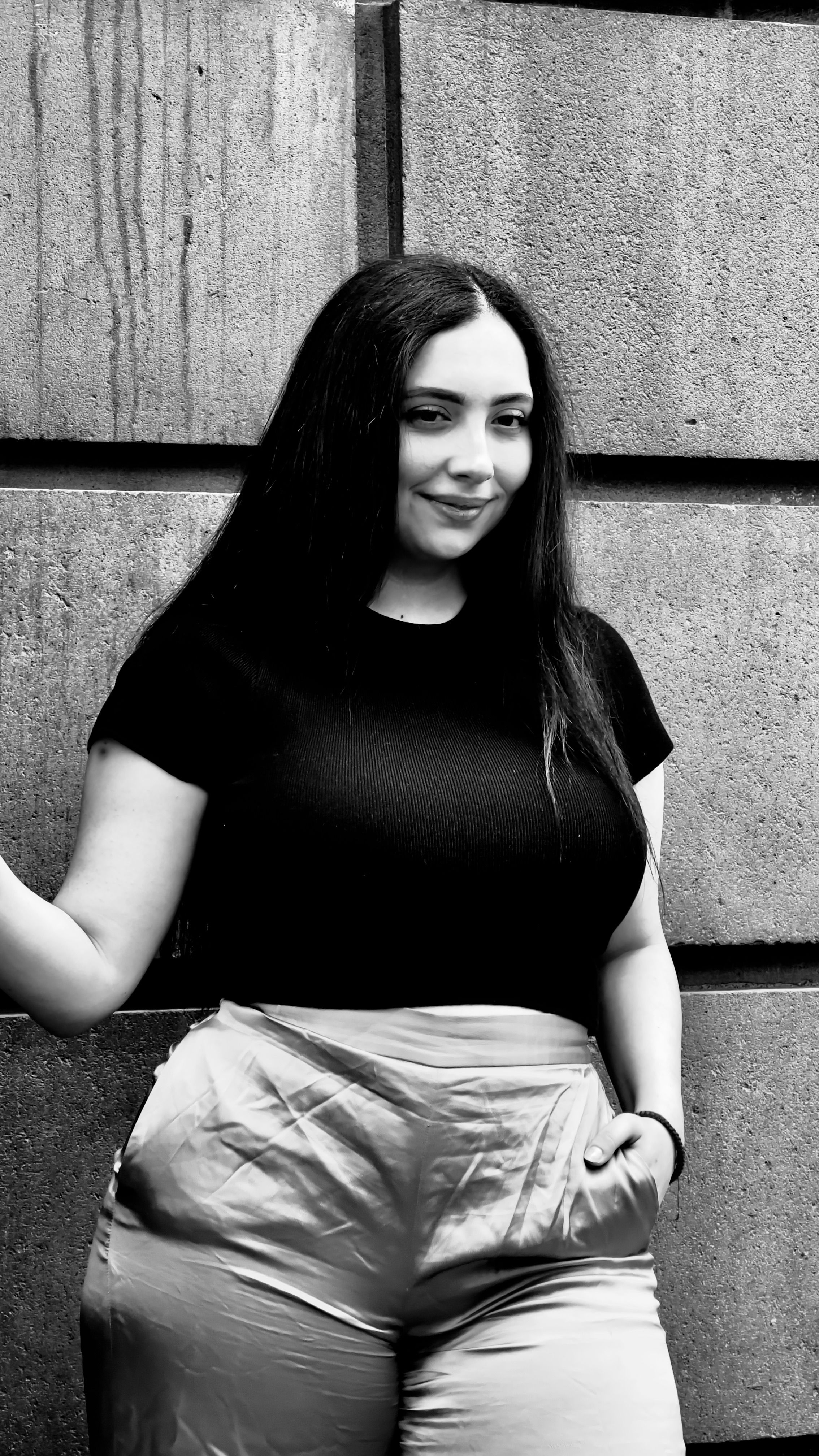 Black and white portrait of a woman posing in fashionable attire.