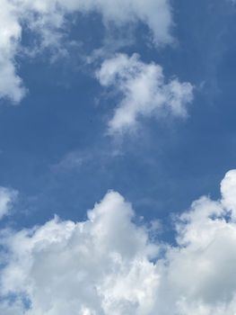 A clear blue sky with fluffy white clouds, perfect for backgrounds or serene scenes.