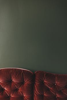 Elegant vintage sofa with plush red cushions set against a dark green wall, offering ample copy space.