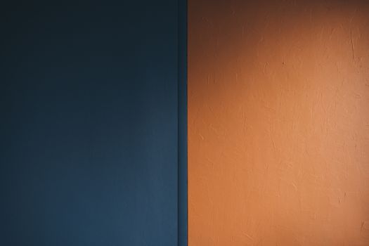 Minimalist photo of a blue and orange textured wall with subtle lighting.