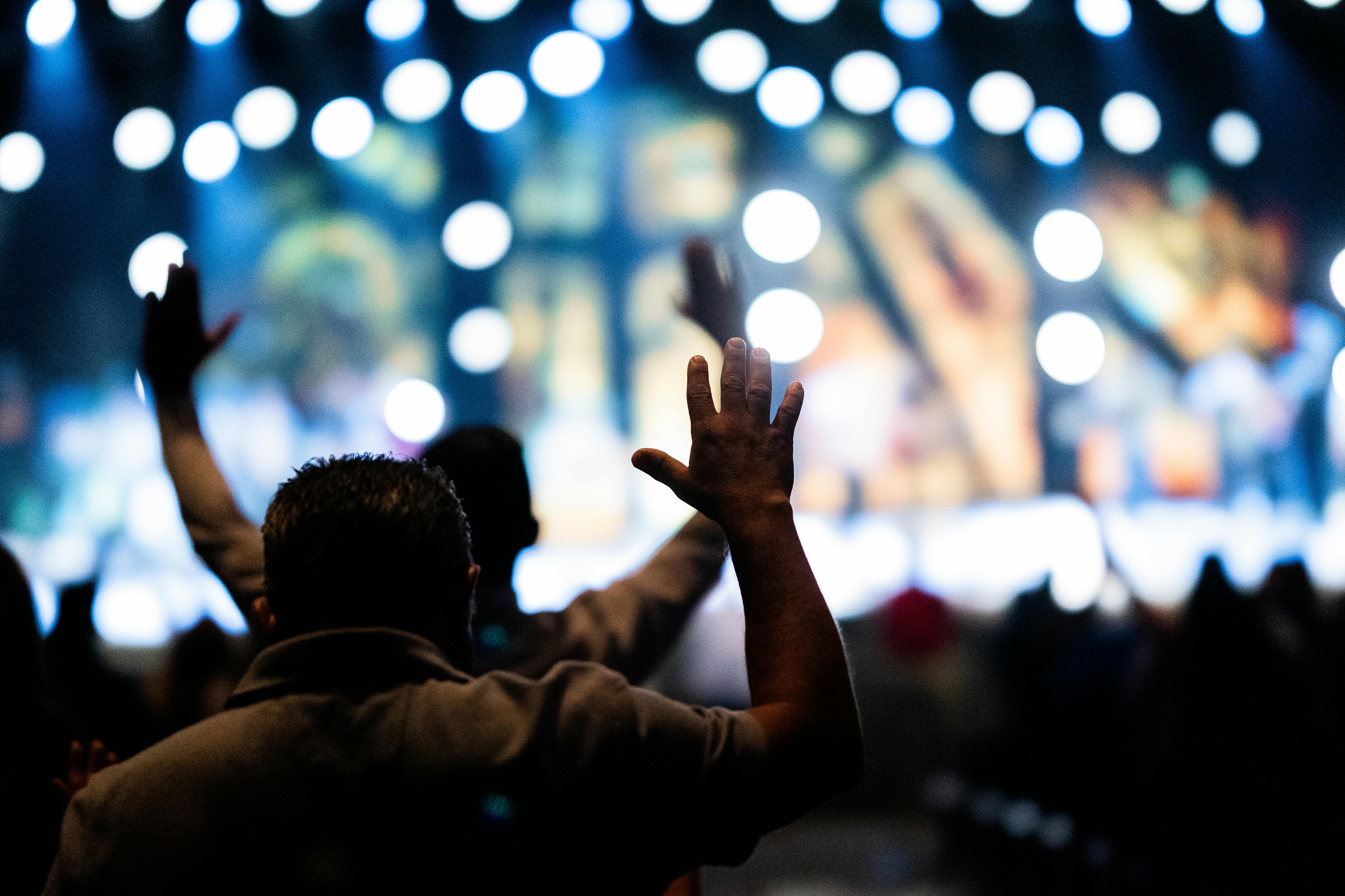 A congregation at Christ Embassy Ho raising hands during worship with a focused, reverent atmosphere