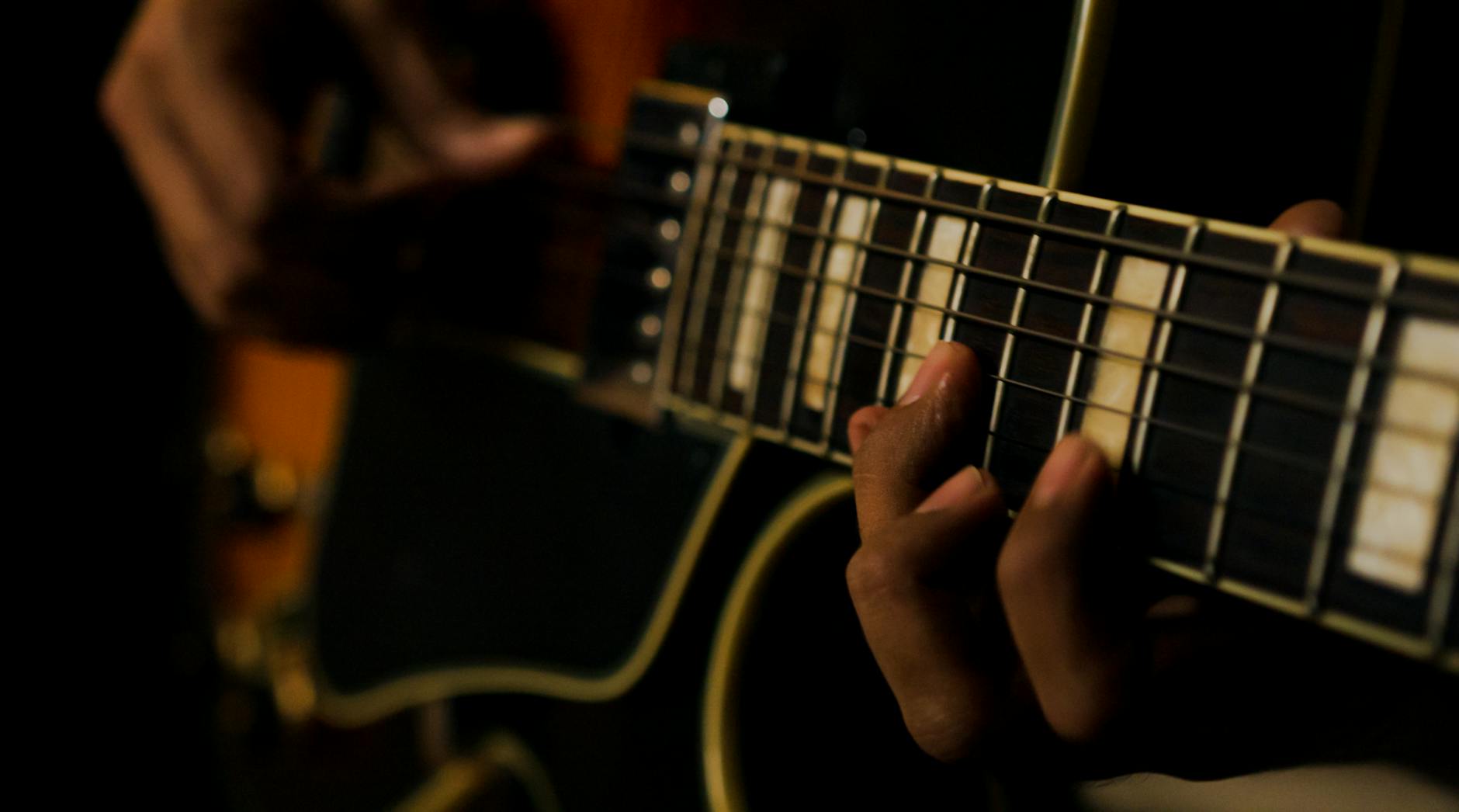 A detailed and intimate view of fingers skillfully playing an electric guitar.