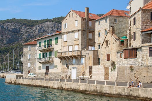Charming stone buildings along a sunlit Croatian waterfront, perfect for travel inspiration.