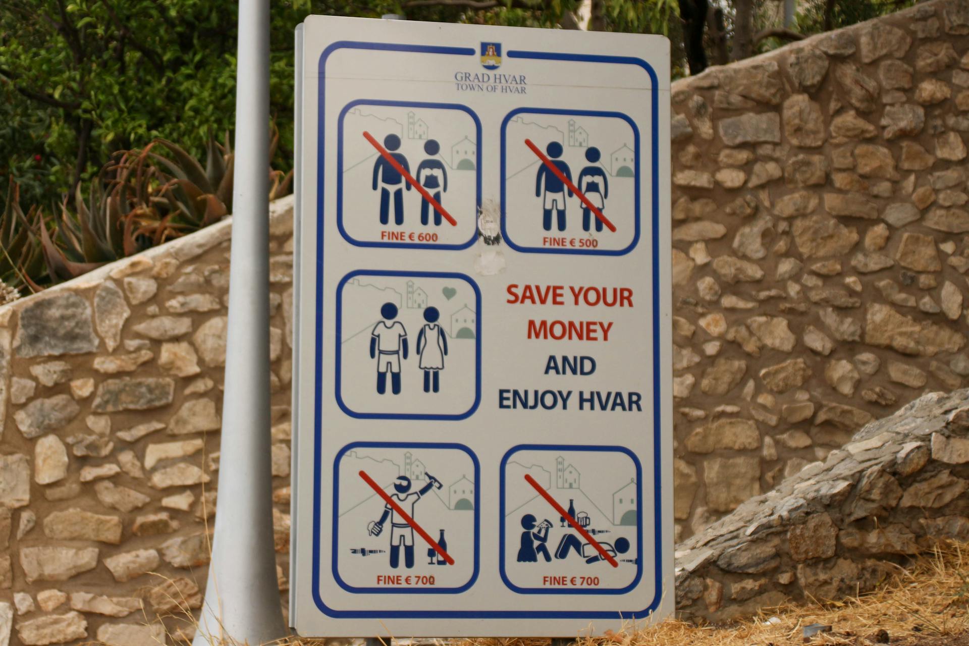 Public notice sign displaying fines for specific actions in Hvar, Croatia.