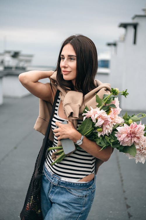 Woman in Black and White Stripe Tank Top Holding Pink Flowers