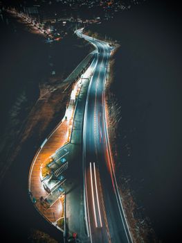 A stunning aerial view of an illuminated road winding through a scenic area at night.