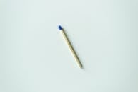 一根简约风格的火柴，白色表面干净，尖端为蓝色