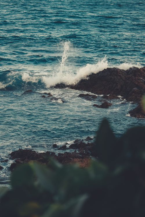 Free Dynamic scene of ocean waves crashing against rugged rocky shore, capturing the power of nature. Stock Photo
