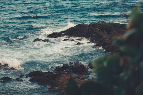Free Vibrant ocean waves crash against rugged rocks, capturing nature's power. Stock Photo