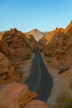 A beautiful paved road winding through a serene canyon landscape at sunrise, capturing nature's raw beauty.