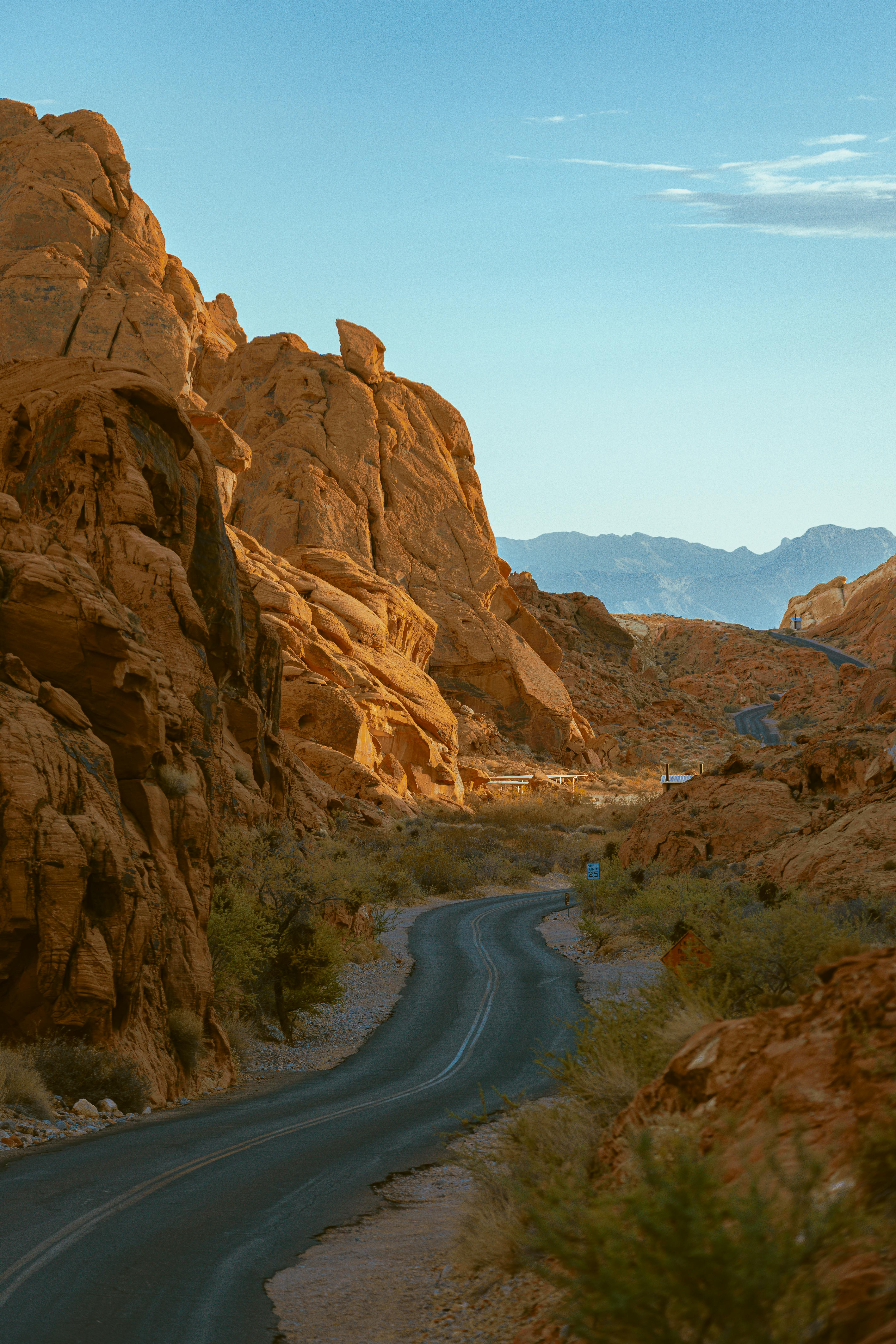 A winding road through a serene desert canyon under a clear blue sky.