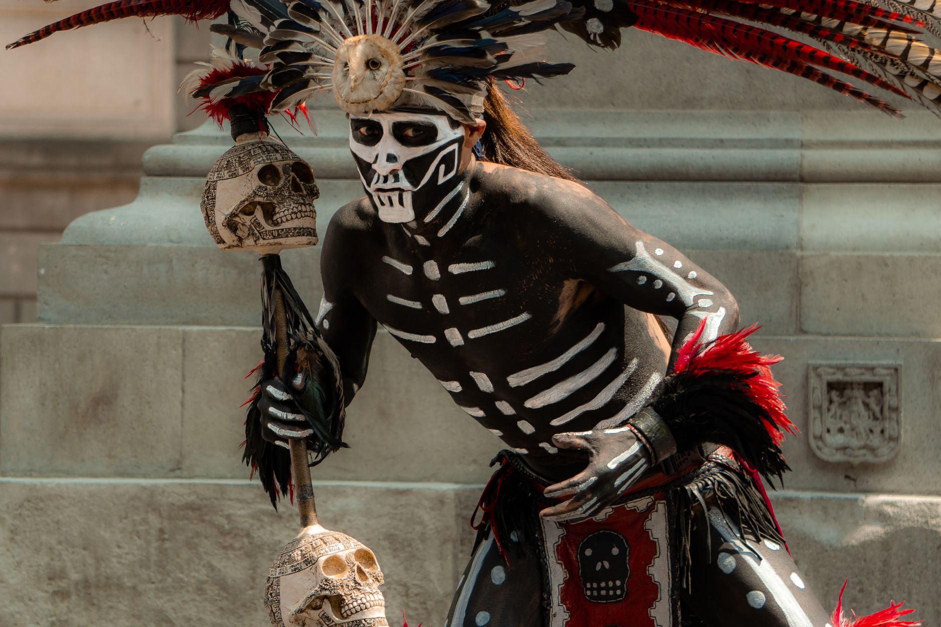 A traditional Mexican warrior with skull face paint and costume.