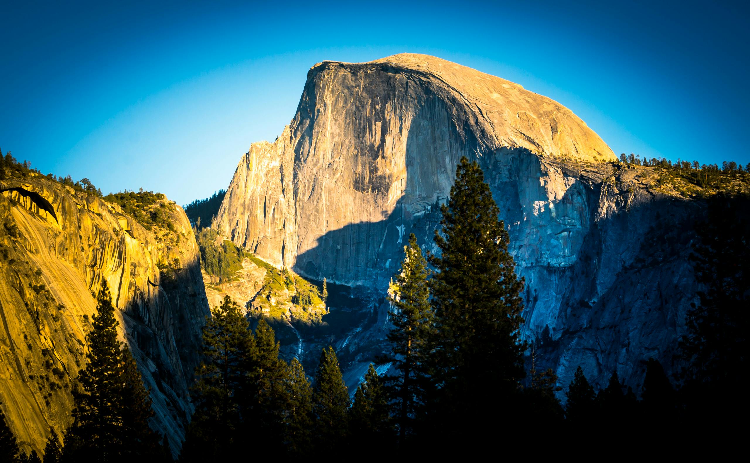 优胜美地的半圆顶景色壮丽，天空蔚蓝，绿植郁郁葱葱