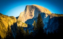 优胜美地的半圆顶景色壮丽，天空蔚蓝，绿植郁郁葱葱