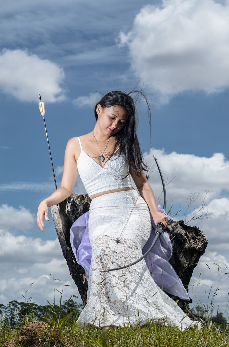 Woman In Dress Sitting With Arbalest In Field