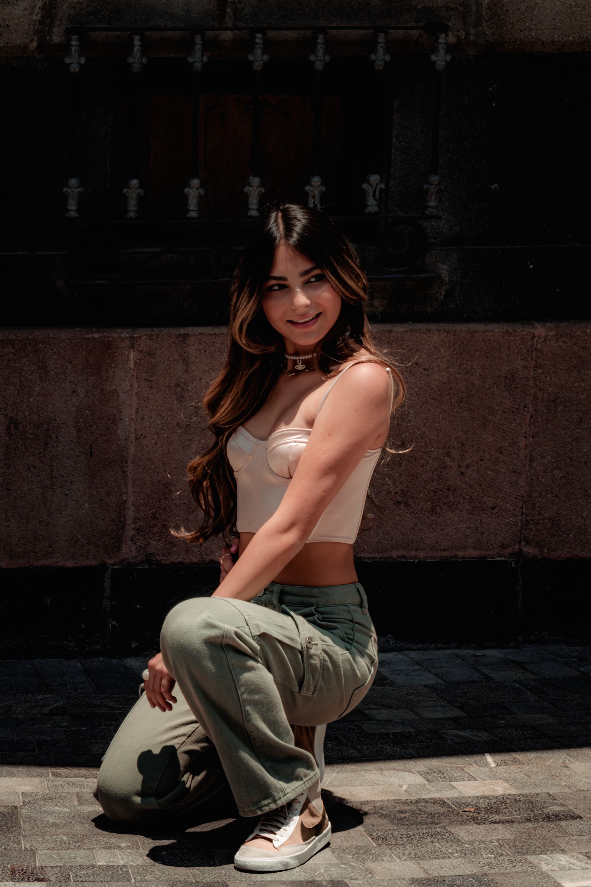 Mulher de top branco e calça cargo cinza