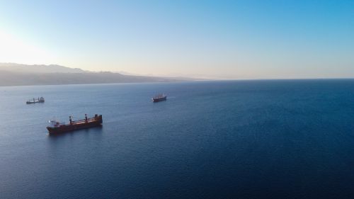Free An aerial view of cargo ships sailing on a tranquil ocean with a clear blue sky. Stock Photo