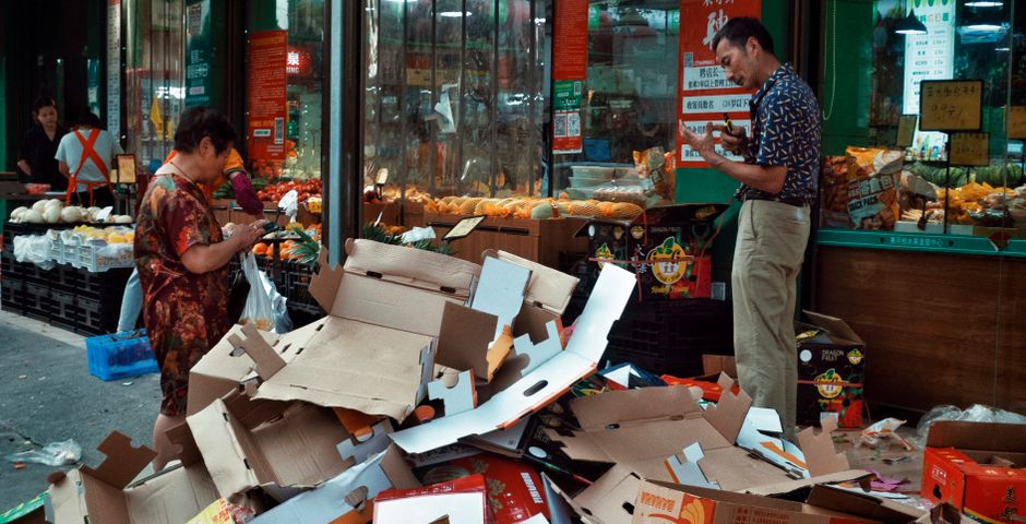 Stacks of cardboard boxes outside a shop — egg cases hitchhike on the underside of grocery and warehouse cardboard