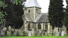 一座古老的教堂坐落于宁静的绿色墓地中，四周环绕着墓碑