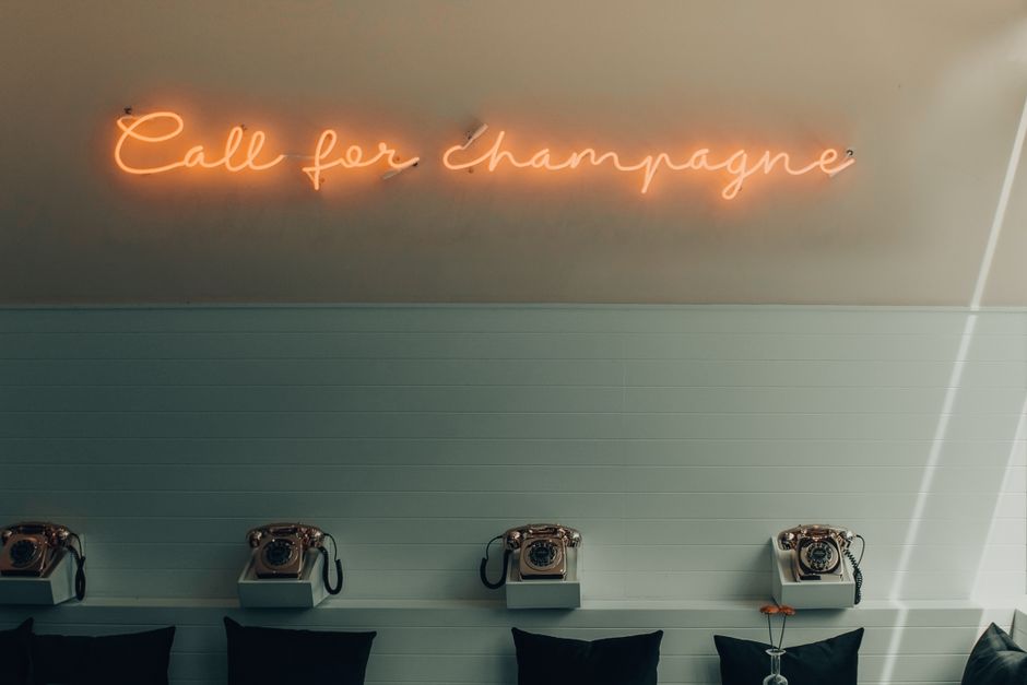Stylish interior featuring retro telephones and a neon 'Call for Champagne' sign.