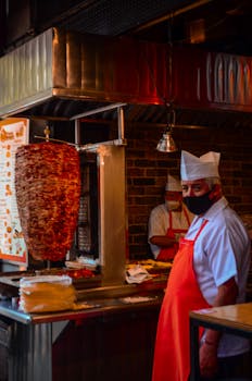Traditional Mexican taqueria with chefs preparing tacos al pastor indoors.