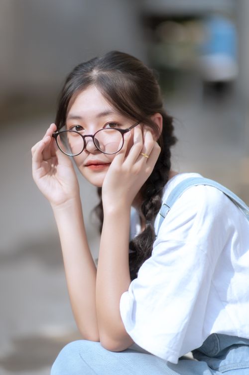 Free Portrait of a young woman with long hair adjusting her eyeglasses indoors. Stock Photo