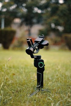 A gimbal stabilizer positioned on green grass with a blurred background.