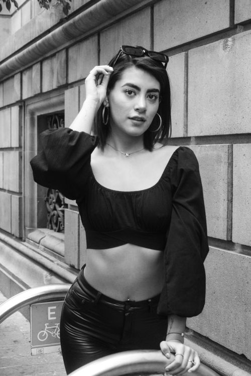 Free Stylish young woman in black outfit posing confidently on city street. Stock Photo