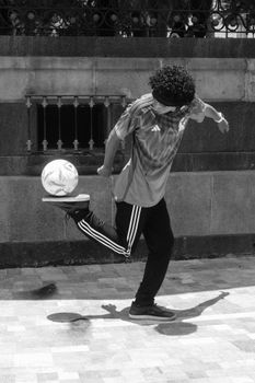 Black and white image of a man performing soccer tricks outdoors, showcasing skill and agility.