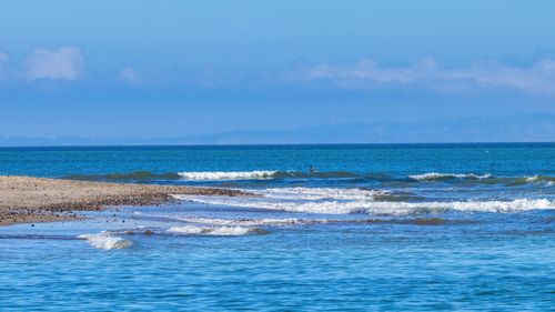 Free A serene beach scene with gentle ocean waves and a clear blue sky. Stock Photo