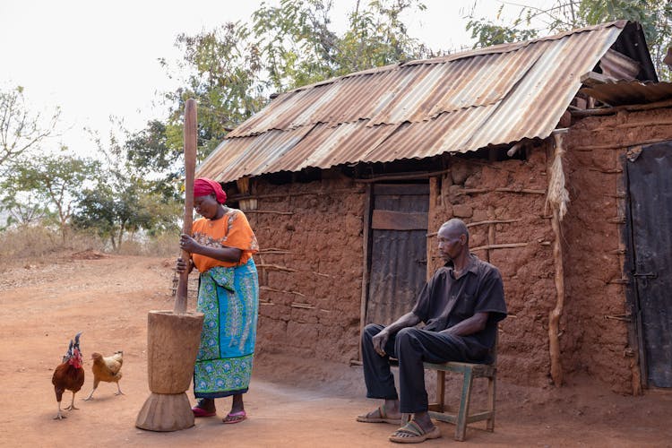 Family Working Near House In Poor Village