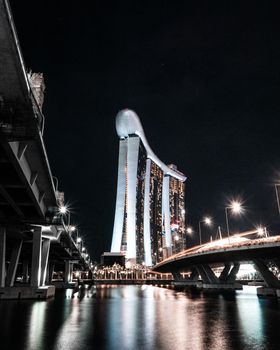 Illuminated Marina Bay Sands and Singapore skyline reflected in the river at night.