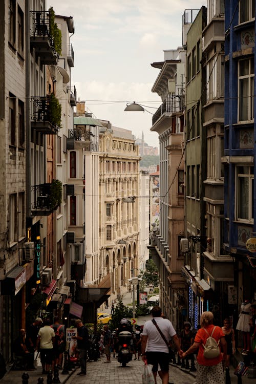 People Walking on Narrow Street between Concrete Buildings