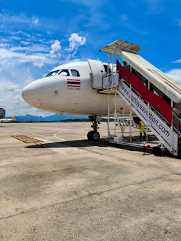 Side view of a passenger airplane at Pattaya Airport with boarding steps on a sunny day.