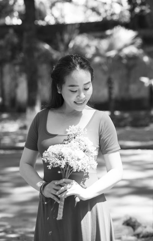 A Grayscale of a Woman Holding a Bouquet of Flowers
