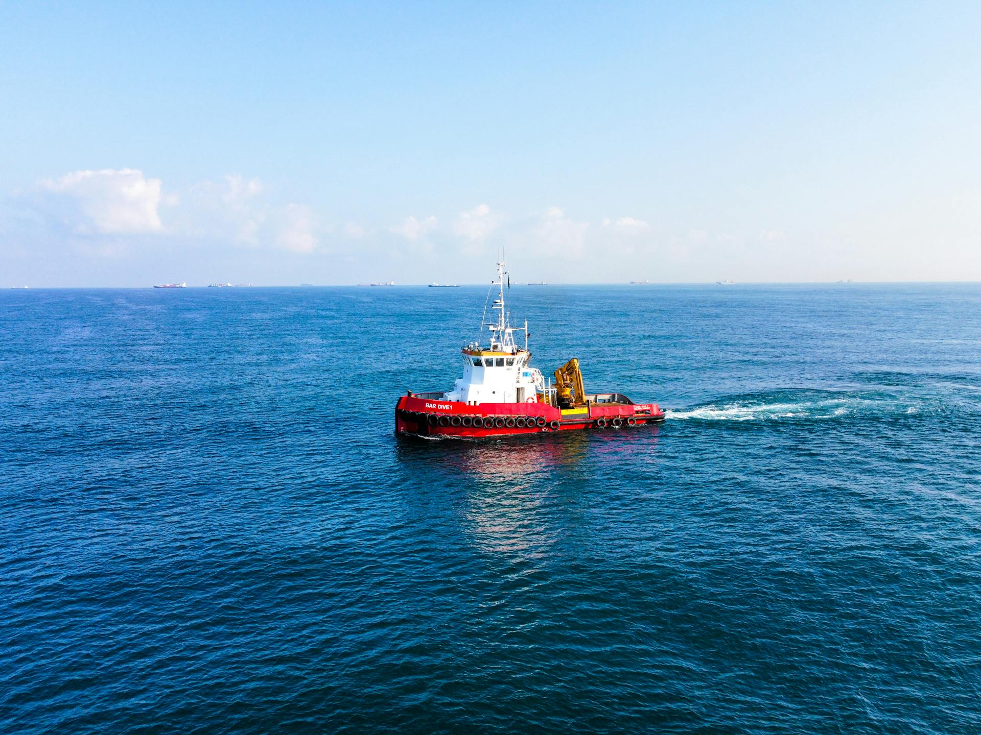 Tugboat navigating calm ocean waters under a clear blue sky.