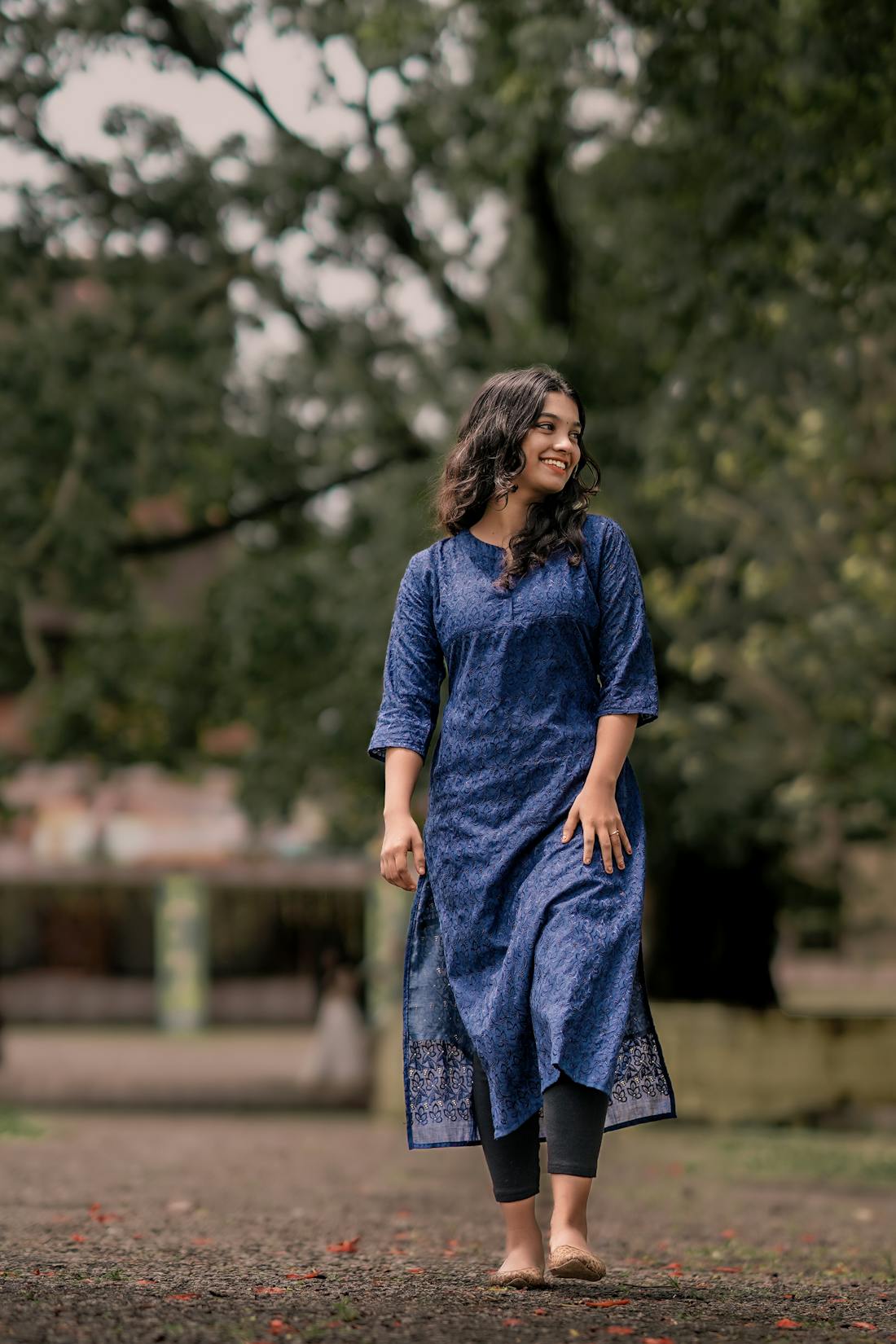 Woman in a breezy blue kaftan-style kurti walking barefoot in a garden
